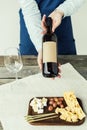 Cropped image of Female sommelier showing a bottle of