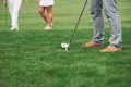 Cropped image of golfer who take aim for the shot. Two friends standing at background Royalty Free Stock Photo