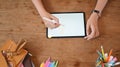 A cropped image of a graphic designer is using a tablet at the wooden working desk Royalty Free Stock Photo