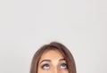 Cropped image half face eyes of woman looking up white grey wall