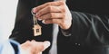 Cropped image Hands of real estate agent offering/giving a house key to smart man in blue shirt . Royalty Free Stock Photo