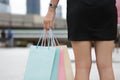 Cropped image of hands of young Asian woman holding shopping bags on city street with copy space. Royalty Free Stock Photo