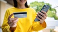 Cropped image of happy young woman holding credit card, paying bill with online payment via internet on smart phone Royalty Free Stock Photo