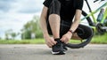 Cropped image of a healthy, fit male cyclist tying his shoelaces before riding a bike