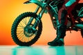 Cropped image of male, biker's leg in boots and tire of motorbike isolated over orange studio background in neon