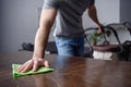 cropped image of man dusting table with rag and holding pram with other hand