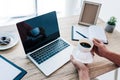 cropped image of man holding cup of coffee at table with laptop, clipboard, textbook, photo frame and place