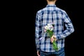 Cropped image man`s hand behind his back with bouquet of wild flowers. Touchingly surprise, gift for your loved one, woman`s day