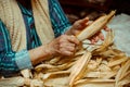 Cropped image of an old lady peeling and selecting with hands corn on a table surrounded by corn peel. Agriculture work.