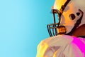 Cropped image of one American football player in sports equipment helmet and gloves isolated on blue studio background Royalty Free Stock Photo