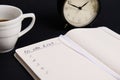 Cropped image of an opened organizer, notepad with list to do on blank white sheets, cup of coffee, alarm clock on black Royalty Free Stock Photo