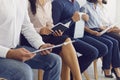 Cropped image of people sitting on chairs in a queue and holding paper in their hands. Royalty Free Stock Photo