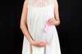 Cropped image of pink socks for a baby girl in pregnant woman`s hands against her belly at black background. Parenthood concept. Royalty Free Stock Photo