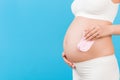 Cropped image of pink socks for a baby girl in pregnant woman`s hands against her belly at blue background. Parenthood concept. Royalty Free Stock Photo