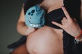 Cropped image pregnant woman holding hat for a baby in her hand and do rock symbol. Motherhood concept. Baby Shower Royalty Free Stock Photo