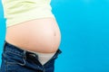 Cropped image of pregnant woman in unzipped jeans showing her baby bump at colorful background with copy space. Waiting for a baby Royalty Free Stock Photo