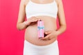 Cropped image of pregnant woman in white underwear holding pink spotted gift box at pink background. Waiting for a baby girl. Copy Royalty Free Stock Photo