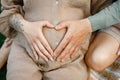 Close up of pregnant woman and her husband making heart shape on belly Royalty Free Stock Photo