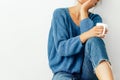 Cropped image of pretty young woman wearing cozy knitted blue sweater and jeans with a mug in her hand. Beautiful woman drinking Royalty Free Stock Photo