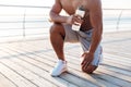 Cropped image of relaxed african sportsman stretching on pier
