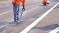 2 road workers marking line for painting traffic color lines on asphalt road with railway track crossing on street surface Royalty Free Stock Photo