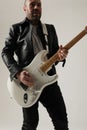 Cropped image of rock musician posing with white guitar indoor. Vertical. Royalty Free Stock Photo