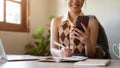 Cropped image of a satisfied Asian woman using her smartphone and taking notes in her book Royalty Free Stock Photo