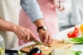 cropped image of senior husband cutting vegetables on wooden board