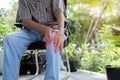 Cropped image of senior man sitting on chair in the garden and having knee pain Royalty Free Stock Photo