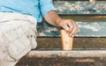 Cropped image of senior man sitting on park bench and holding reusable or easily recyclable bamboo cup for take away coffee Royalty Free Stock Photo