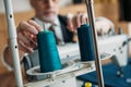 cropped image of senior tailor touching spool of thread on sewing machine at sewing workshop Royalty Free Stock Photo