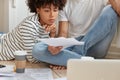 Cropped image of serious black woman and her partner look attentively at documents, develop startup project, work at