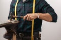 Cropped image of a shoemaker measuring a shoe with measure tape in workshop