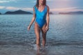 Cropped image of slim young woman wearing trendy blue swimsuit walking in the sea at sunset Royalty Free Stock Photo