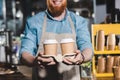 cropped image of smiling male barista holding two disposable cups of