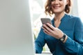 Cropped image of a smiling young woman holding mobile phone