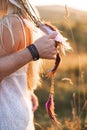 Cropped image of stylish couple, boho woman in white dress and feather accessories in the hair, and hands of man hugging