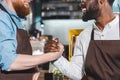 cropped image of two smiling owners of coffee shop shaking