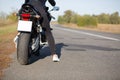 Cropped image of unrecognizable female bikes poses back on bike at asphalt, wears black clothes, blank copy space aside for your a