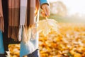 Cropped image of unrecognosable woman wearing blue coat in autumn yellow foliage walking in park or forest holding maple Royalty Free Stock Photo