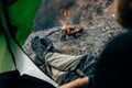 Cropped image of a view from tent entrance of young traveler man relaxing in mountains near to bonfire Royalty Free Stock Photo