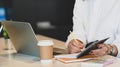 Cropped image waist up of businesswoman taking notes/writing on notebook that putting on white working table. Royalty Free Stock Photo