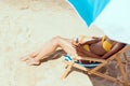 cropped image of woman in bikini laying on deck chair and holding cocktail in coconut shell under beach umbrella Royalty Free Stock Photo