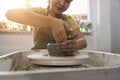 Cropped image of woman ceramist creating handicraft crockery on the pottery wheel in creative studio workshop