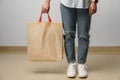 Cropped image of woman holding beige shopping bag in studio