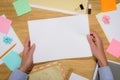 cropped image of woman holding empty white paper over table with stationery