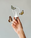 Cropped image of woman holding a lamp with butterflies in her hand