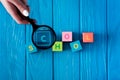 cropped image of woman holding magnifier above lettering school made from cubes on wooden blue