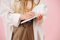 Cropped image of a woman with in loose clothes writing in a notebook over pink Royalty Free Stock Photo