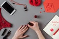 cropped image of woman painting nails with red polish, notebook with words